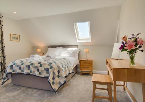 a bedroom with a bed with a vase of flowers at Peaty Cottage in Panxworth
