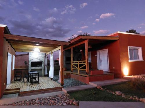 a house with a deck with a table and a kitchen at Cabañas Los Mochuelos in Villa Cura Brochero