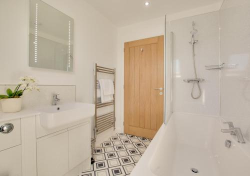 a white bathroom with a sink and a shower at Peaty Cottage in Panxworth