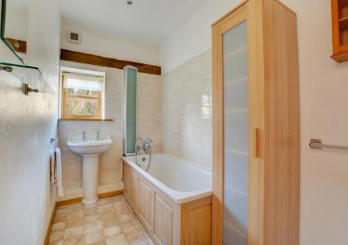 a bathroom with a tub and a sink at Rectory Barn in Ashwellthorpe