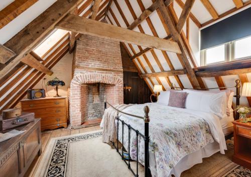 a bedroom with a bed and a brick fireplace at Reclaim Cottage in Colkirk