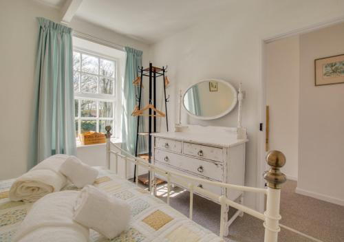 a bedroom with a bed and a mirror and a dresser at Reeve Cottage in Blakeney