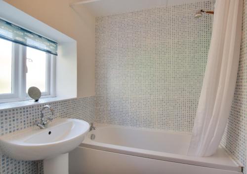 a bathroom with a sink and a tub and a sink and a mirror at Reeve Cottage in Blakeney