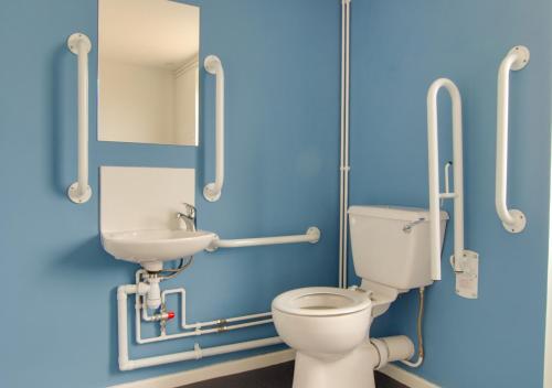 a blue bathroom with a toilet and a sink at Sailing Club Bungalow in Wolferton