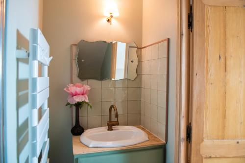 a bathroom with a sink and a vase with a flower at Chez Agnès in Pont-lʼÉvêque