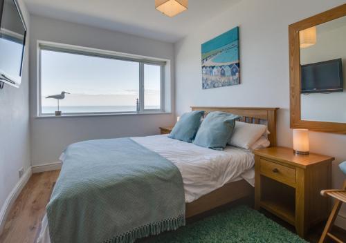 a bedroom with a bed and a large window at Seaspray in Sheringham