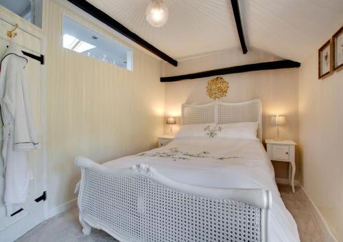 a white bedroom with a white bed and a window at Robin Cottage in North Elmham