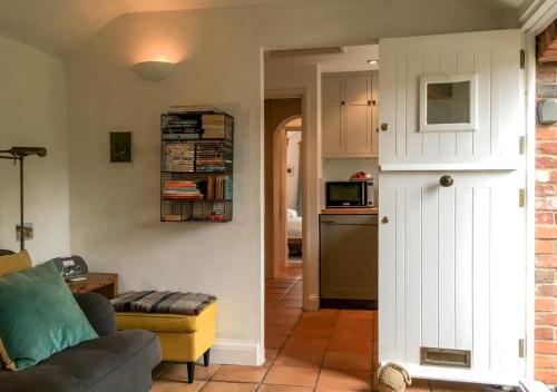 a living room with a couch and a kitchen at Poppy Cottage in Stiffkey