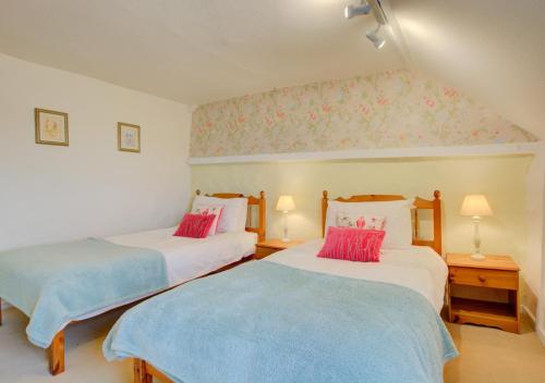 two beds in a room with pink and blue sheets at Shamrock Cottage in Hindringham
