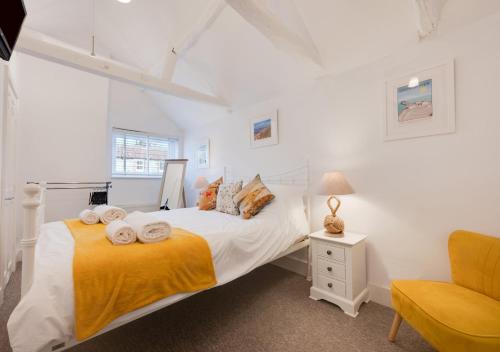 a white bedroom with a bed and a chair at Silvergate Cottage in West Runton
