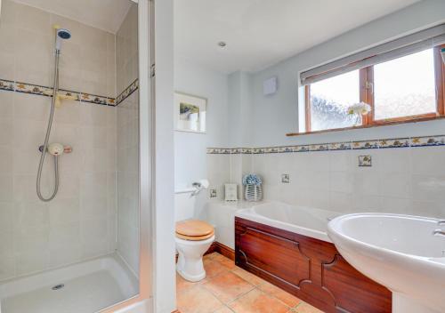 a bathroom with a tub and a toilet and a sink at Swallow Barn in Bodham