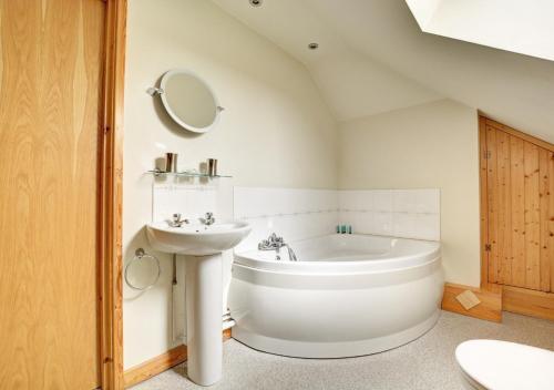 a bathroom with a white tub and a sink at Skipjack in Ingworth