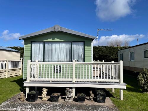 a green house with a bench in a yard at 6 berth pet friendly caravan on Sandy Glade (John Fowlers) Brean in Berrow