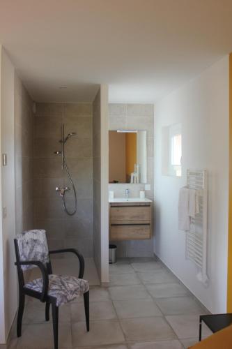 uma casa de banho com um chuveiro, uma cadeira e um lavatório. em Gîte de charme pour 10 personnes em Camélas
