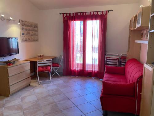 a living room with a red couch and a desk at Casa Antonella in Santa Teresa Gallura
