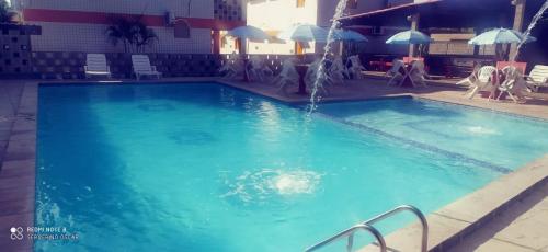 a large swimming pool with a water fountain at Flats quase beira mar ar piscinas estac caseiro in Itamaracá