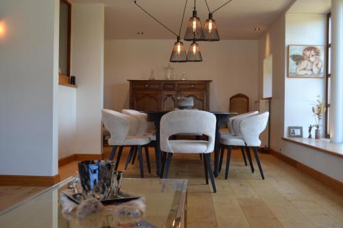 a dining room with a table and white chairs at Bidi's Lodge in Stavelot