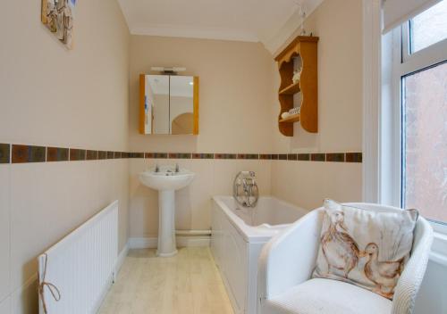 a bathroom with a bath tub and a sink at Staithe Cottage in Heacham