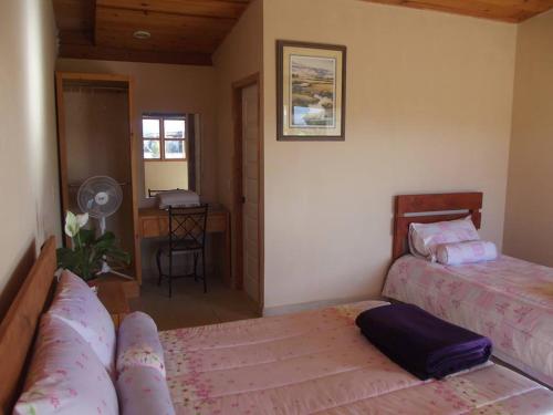 a bedroom with two beds and a desk with a fan at Casa Campo Rancho Villarino in Ensenada