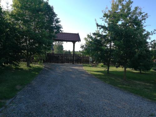 a gravel road with a wooden fence and trees at Dom z bala kort tenisowy ,linia brzegowa plaża ,pomost ,kajaki, łódka in Krzywe