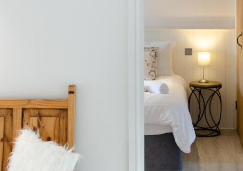 a bedroom with a bed with white sheets and a lamp at The Granary in Banningham