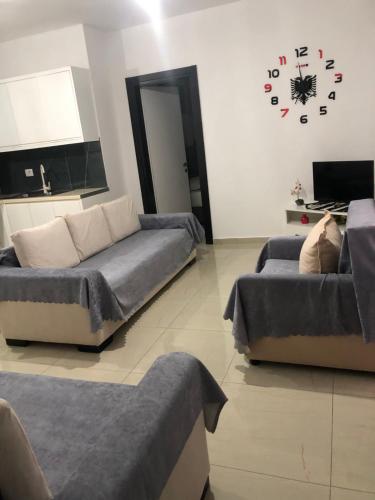 a living room with two couches and a clock on the wall at Vila Xhafa in Ksamil