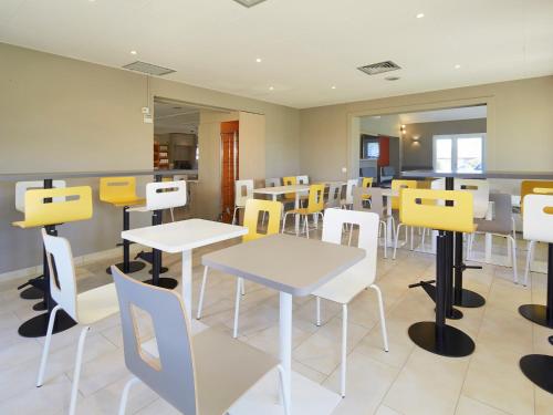 a restaurant with white tables and yellow chairs at Premiere Classe Poitiers Futuroscope - Chasseneuil in Chasseneuil-du-Poitou