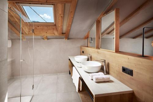 a bathroom with two sinks and a glass shower at Hotel-Garni Ehrenfels in Schenna