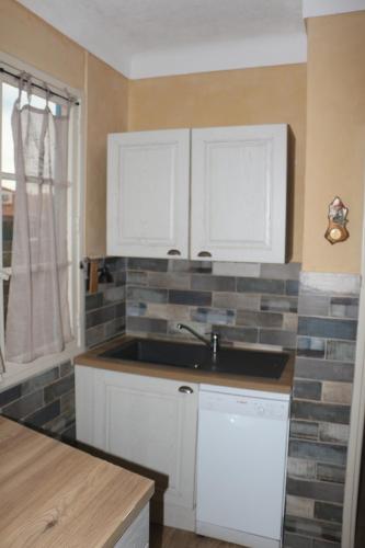 une cuisine avec des armoires blanches et un évier dans l'établissement Maison de pêcheurs climatisée bord de mer, à Saint Cyprien Plage