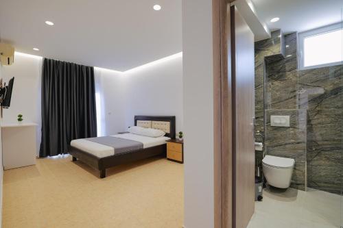 een slaapkamer met een bed en een glazen douche bij Apartments & Hotel Eleanna in Sarandë