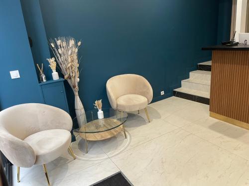 2 Stühle und ein Tisch in einem Zimmer mit Treppen in der Unterkunft Hôtel P.L.M. in Cannes