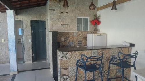 a kitchen with a counter with chairs and a refrigerator at Casa de Veraneio in Maricá