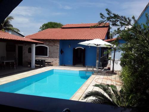 a villa with a swimming pool and a house at Casa de Veraneio in Maricá