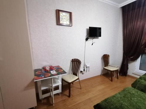 a living room with a table and chairs and a bed at Квартира in Baku