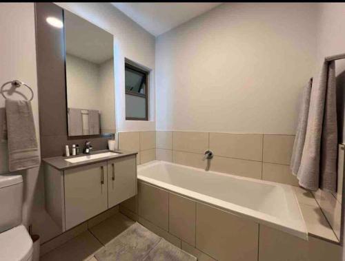 a bathroom with a tub and a sink and a toilet at Lovely and Cosy 2 bedrooms Space in Rosebank in Johannesburg