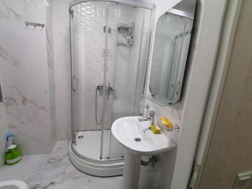 a white bathroom with a shower and a sink at Квартира in Baku