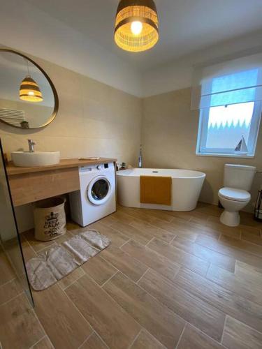 a bathroom with a tub and a sink and a washing machine at Hillside Apartman in Dunaszentmiklós
