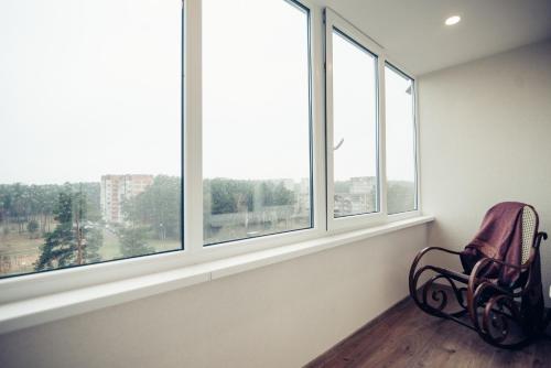 uma cadeira num quarto com janelas em Pine Apartment em Visaginas