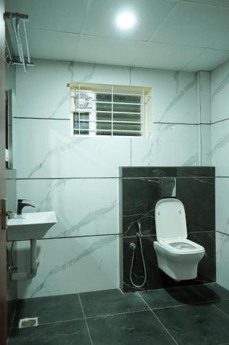 a bathroom with a toilet and a sink at HOTEL NIVETHA INN in Coimbatore