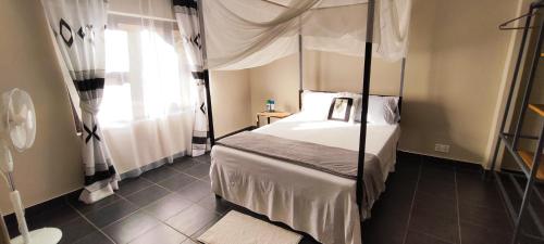 1 dormitorio con cama con dosel y ventana en Kalahari Sand Ridge Inn en Livingstone