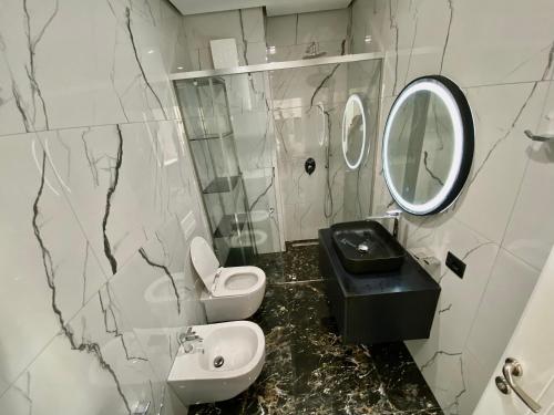 ein Badezimmer mit einem Waschbecken, einem WC und einem Spiegel in der Unterkunft Lux Apartment 02 + Free Parking Post in Tirana