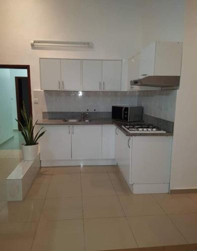 een keuken met witte kasten en een fornuis met oven bij RESIDENCE OLUSHOLA in Cotonou