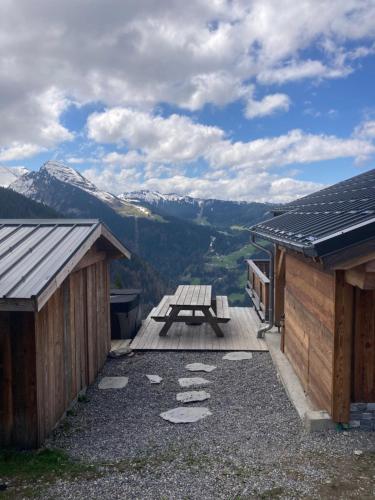 a picnic table on a deck with mountains in the background at Chalet avec jacuzzi - 150 m des remontées in Morzine