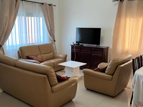 een woonkamer met 2 banken en een flatscreen-tv bij RESIDENCE OLUSHOLA in Cotonou