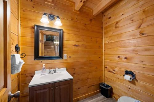 a bathroom with wooden walls and a sink and a mirror at 2-Bedroom Cabin with 2 Master Suites, Loft, Half-Bath and hot tub in a Serene Resort Setting in Sevierville