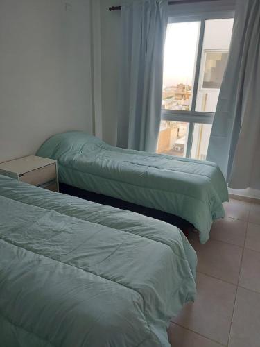 2 camas en una habitación con ventana en DEPARTAMENTO CENTRICO CATAMARCA en San Fernando del Valle de Catamarca