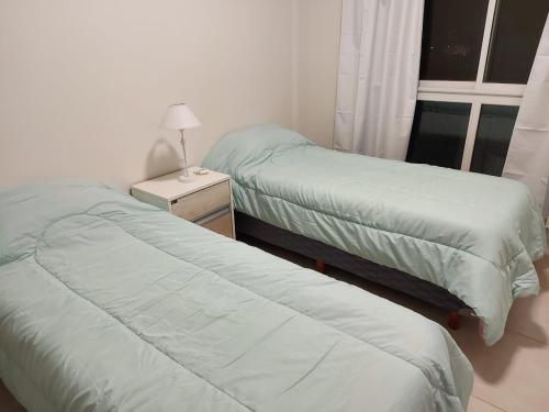 1 dormitorio con 2 camas y mesita de noche con lámpara en DEPARTAMENTO CENTRICO CATAMARCA en San Fernando del Valle de Catamarca