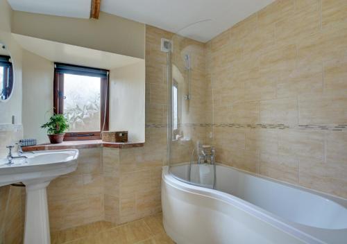 ein Badezimmer mit einer Badewanne und einem Waschbecken in der Unterkunft The Hay House in Thursford