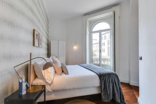 biała sypialnia z łóżkiem i oknem w obiekcie Sweet Inn - Arco della Pace w Mediolanie