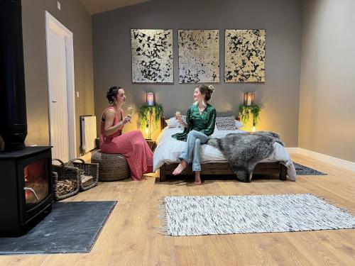 two women sitting on a bed in a living room at Quirky, Luxury Hideaway in Llanbrynmair